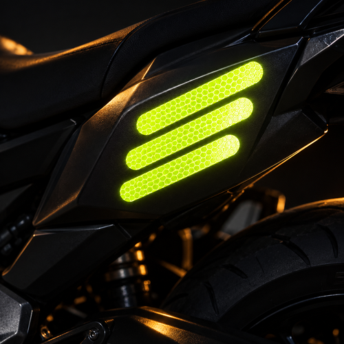 Bandes réfléchissantes collées sur le flanc d'une moto, renvoyant la lumière des phares la nuit
